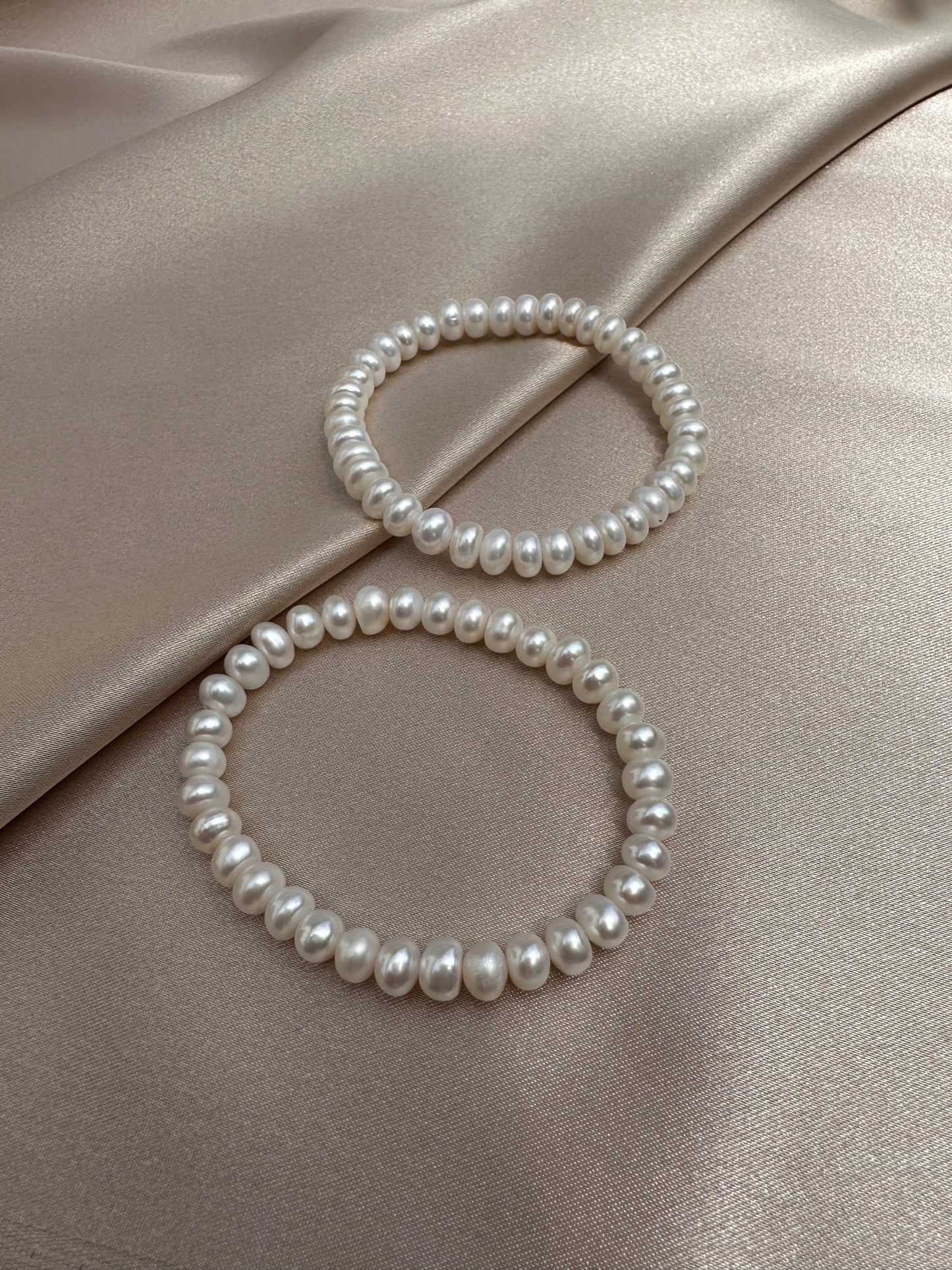 OS pair of white pearl bracelets.